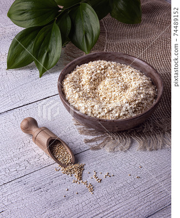 White quinoa flakes in clay bowl and quinoa seeds on table White quinoa flakes in clay bowl and quinoa seeds on table 74489152