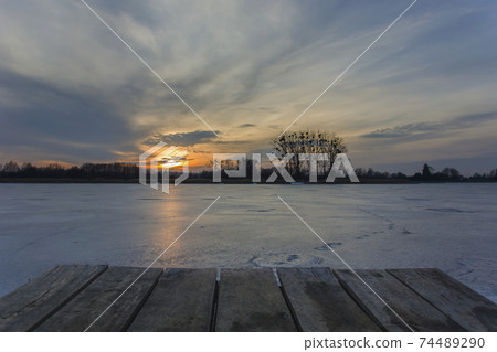 Platform of planks on a frozen lake, beautiful sunset on the sky Platform of planks on a frozen lake, beautiful sunset on the sky 74489290
