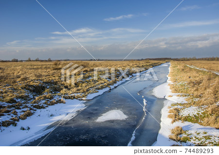Frozen river and dry meadows, view on winter day Frozen river and dry meadows, view on winter day 74489293