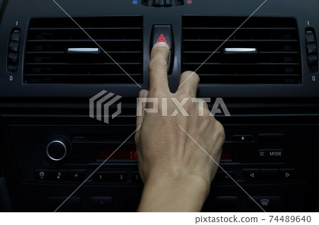 Close up hand press the emergency light in the car, Fingers press button.for open the contract emergency light in car. Emergency button press for open emergency light warning sign symbol out side car Close up hand press the emergency light in the car, Fingers press button.for open the contract emergency light in car. Emergency button press for open emergency light warning sign symbol out side car 74489640