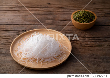 Fresh Glass Noodle (Transparent bean vermicelli) on wooden plate with Green beans on spoon Fresh Glass Noodle (Transparent bean vermicelli) on wooden plate with Green beans on spoon 74492231