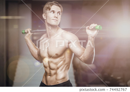Fitness man at workout in gym with bodybar stretching muscles 74492767