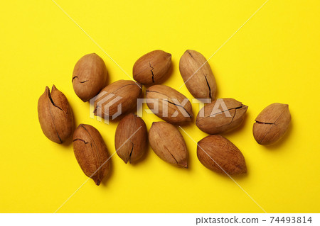 Tasty pecan nuts on yellow background, top view Tasty pecan nuts on yellow background, top view 74493814