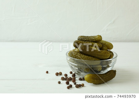 Glass bowl with pickled cucumbers on white wooden background Glass bowl with pickled cucumbers on white wooden background 74493970