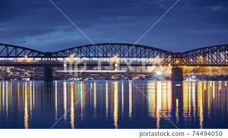 Passenger train passing over railway bridge against city 74494050