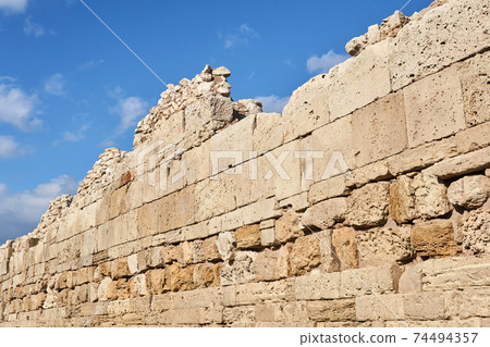 fragment of a destroyed antique fortress wall with masonry from different centuries against the sky fragment of a destroyed antique fortress wall with masonry from different centuries against the sky 74494357