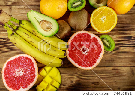 Assortment of tropical fruits on wooden table. Still life with bananas, mango, oranges, avocado, grapefruit and kiwi fruits 74495981