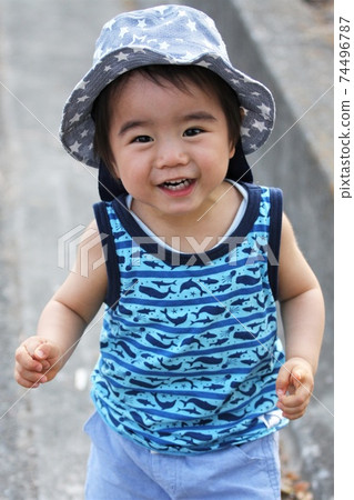 A 2-year-old boy wearing a tulip hat and taking a walk in a tank top 74496787