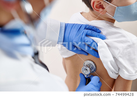 Close up of pediatrician using stethoscope, checking up heartbeat and lungs while auscultation in doctor office 74499428