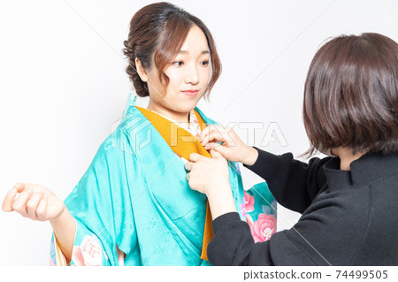 A woman who has a kimono dressed and a woman who is a dresser 74499505