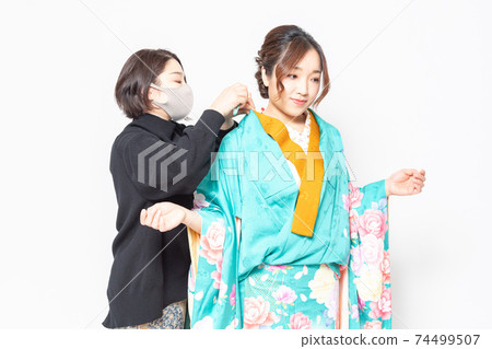 A woman who has a kimono dressed and a woman who is a dresser 74499507