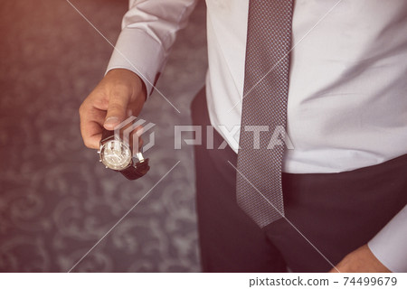 businessman looking at his watch on his hand, watching the time businessman looking at his watch on his hand, watching the time 74499679