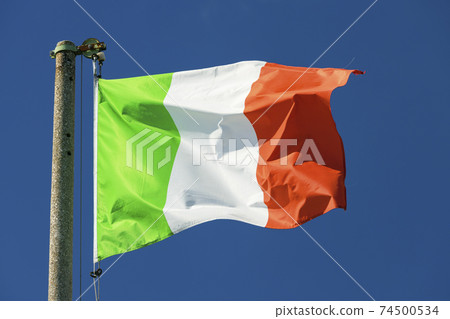 Italian flag blowing in the wind in the blue sky 74500534