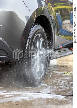 Manual car wash with pressurized water. Cleaning front part of car with high pressure water. Manual car wash with pressurized water. Cleaning front part of car with high pressure water. 74500635