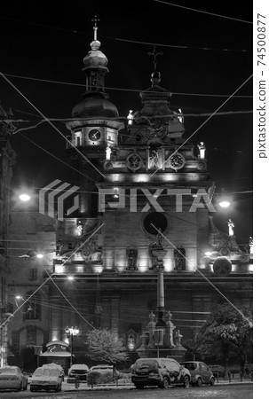 Grayscale. Night winter Lviv city (Ukraine) cityscape. Bernardine Church and monastery (church of St. Andrew) top, built in17th century. And Monument to Saint John of Dukla ahead, built in 1736. 74500877