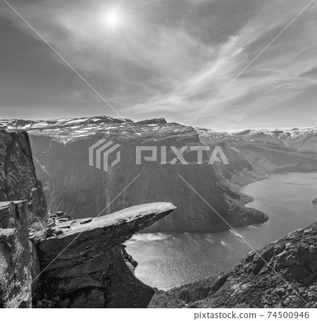 Grayscale. Summer sunshiny view of Trolltunga (famous The Troll's tongue Norvegian destination) and Ringedalsvatnet lake in Odda, Roldal, Norway. Grayscale. Summer sunshiny view of Trolltunga (famous The Troll's tongue Norvegian destination) and Ringedalsvatnet lake in Odda, Roldal, Norway. 74500946