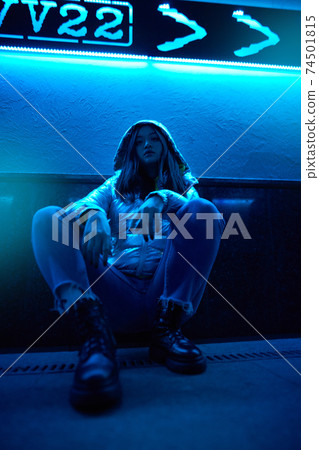 Young adult hipster woman sitting under glowing neon light 74501815