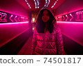 Neon Style. Asian girl in glossy jacket standing in the corridor with fluorescent pink lights looking camera confident 74501817