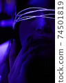 Young adult millennial woman in bright neon light, touching her lips with fingers 74501819