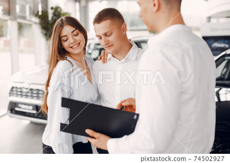 Stylish and elegant couple in a car salon 74502927