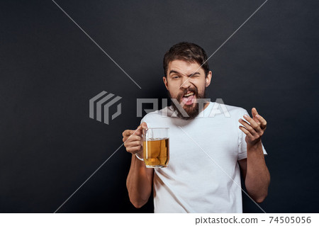 Man with a mug of beer in his hands emotions fun lifestyle white t-shirt dark isolated background 74505056