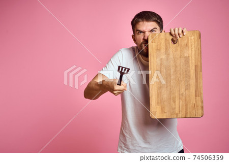 guy holding kitchen board and spatula in hand on pink background cropped view 74506359