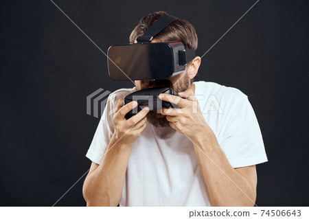 man wearing virtual reality glasses with gamepad in hand technology games leisure dark background 74506643