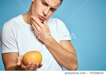 Happy man with fresh fruits gesturing with hands blue background white t-shirt vitamins oranges Happy man with fresh fruits gesturing with hands blue background white t-shirt vitamins oranges 74506650