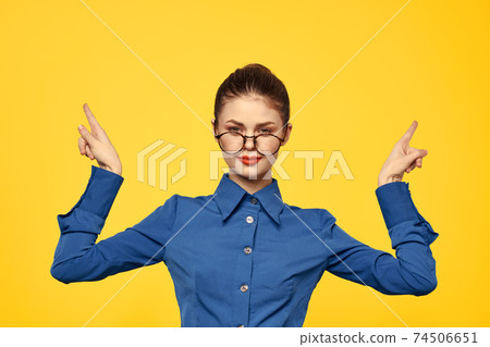 A woman in a blue shirt and glasses with bright makeup on her face is gesturing with her hands Copy Space 74506651