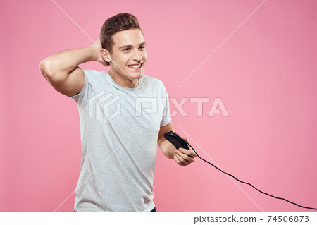 Cheerful man with joystick wire technology entertainment lifestyle pink background 74506873