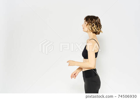 Slender woman in leggings on a light background doing fitness gymnastics exercises 74506930