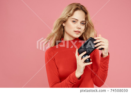 Woman with gamepad in hand entertainment video games lifestyle technology red blouse pink background Woman with gamepad in hand entertainment video games lifestyle technology red blouse pink background 74508030
