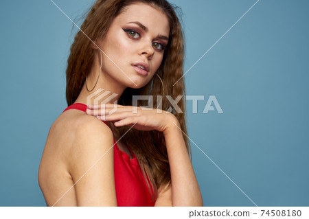 Woman with wavy hair attractive look Red tank top blue background Woman with wavy hair attractive look Red tank top blue background 74508180