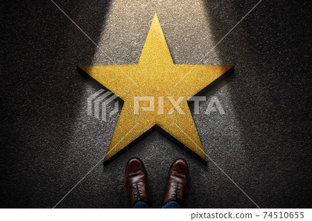 Success in Business or Personal Talent Concept. Top View of Business Person in Working Shoes Standing in front of a Golden Star. Light Shining on the Dark Cement Floor Success in Business or Personal Talent Concept. Top View of Business Person in Working Shoes Standing in front of a Golden Star. Light Shining on the Dark Cement Floor 74510655