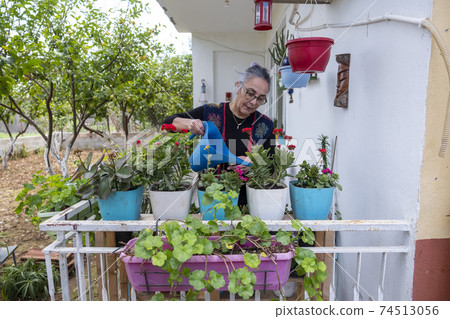 Cheerful girl watering flowers 74513056