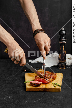 Cutting juicy steak on wooden cutting board 74513242