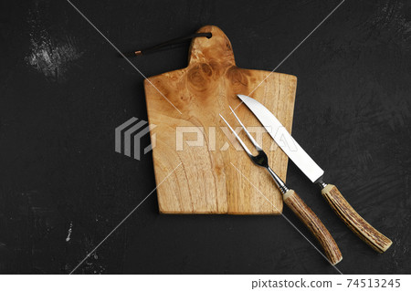 Knife and fork for steak on empty wooden cutting board Knife and fork for steak on empty wooden cutting board 74513245