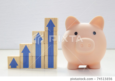 A piggy bank with wood blocks stacking as step stair with blue arrows up. Concept: Successful business, Business growth, Savings growth, Interest rate. Long term savings. A piggy bank with wood blocks stacking as step stair with blue arrows up. Concept: Successful business, Business growth, Savings growth, Interest rate. Long term savings. 74513856