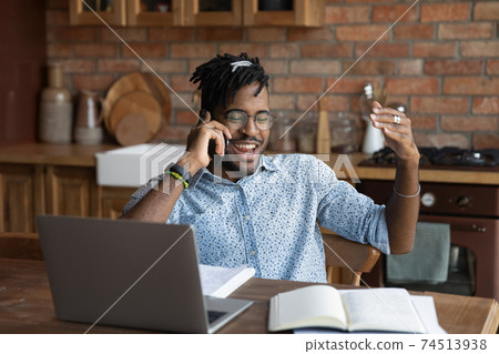 Overjoyed African American man talking on phone, distracted from work Overjoyed African American man talking on phone, distracted from work 74513938