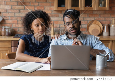 Close up serious African American couple looking at laptop screen 74514298