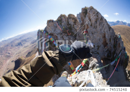 Hiker looking at the altitude with sports watch on high altitude mountain peak 74515248
