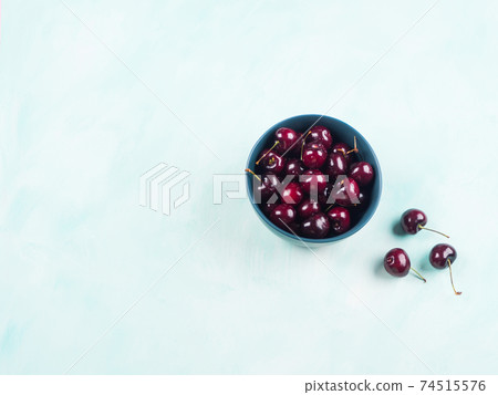 Fresh summer cherries in bowl on turquoise background 74515576