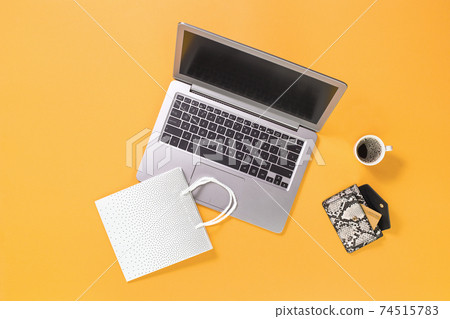 Laptop with shopping bags on trendy yellow orange background Laptop with shopping bags on trendy yellow orange background 74515783