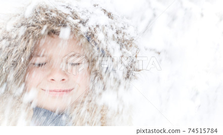Child face with closed eyes smiling with blurred snow falling Child face with closed eyes smiling with blurred snow falling 74515784
