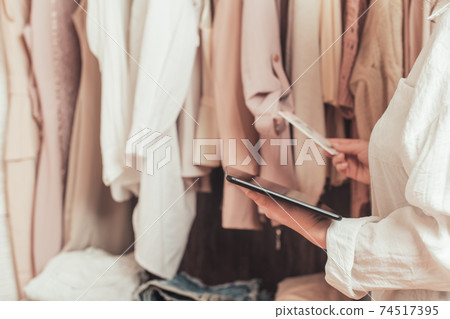 Female entrepreneur holding tablet while doing inventory in her trendy clothing shop Female entrepreneur holding tablet while doing inventory in her trendy clothing shop 74517395