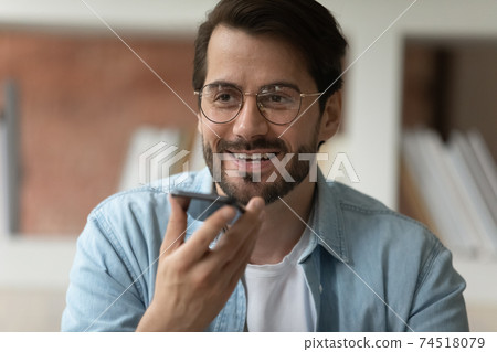 Smiling man talk on cellphone device on loudspeaker 74518079
