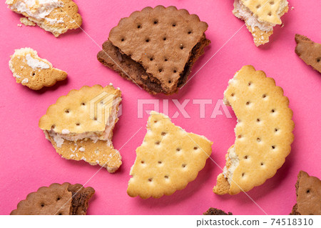 Pieces of chocolate chip cookies and biscuits with filling on a pink background close-up 74518310