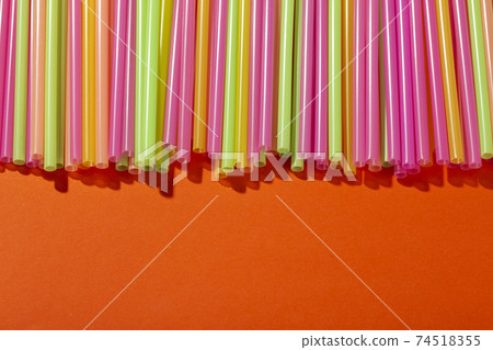 Colored tubules for juice and cocktails on orange background. Space for text. 74518355