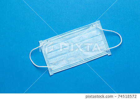 Surgical masks with rubber ear straps on a green background.  Surgical masks with rubber ear straps on a green background.  74518572