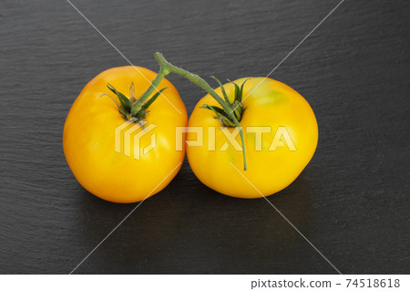 Two yellow tomatoes on a black board. Foods that are low in sugar. 74518618
